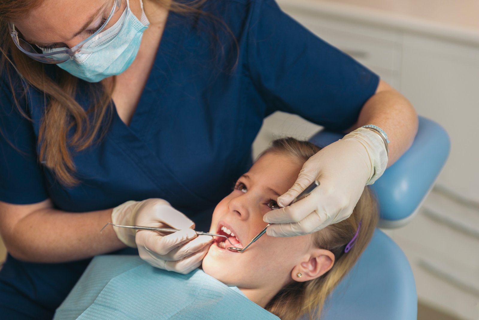 Dentists with a patient during a dental intervention to girl.